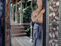 David Bowie stojí u pozlacených dveří obývacího pokoje v balijském stylu.